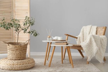 İçinde zeytin ağacı, masa ve koltuk olan bir oturma odası.