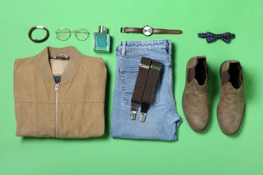 Erkek giysileri, farklı aksesuarlar ve yeşil arka planda ayakkabılar.