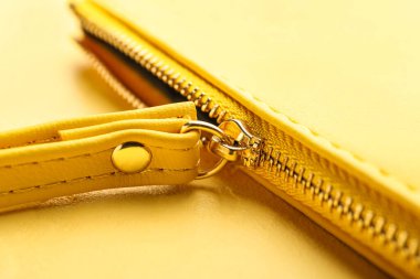 Sarı arka planda metal fermuarlı kozmetik çanta, yakın plan.