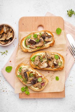 Hafif arka planda krem peynirli ve mantarlı ahşap ekmek tahtası.