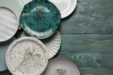 Yeşil ahşap arka planda farklı plakalar ve çiçek dekoru.