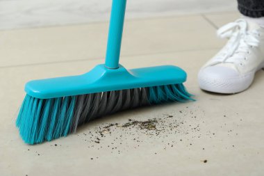 Kadın süpürgeyle yerleri süpürüyor, yakın plan.