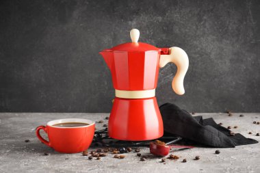 Gayzer kahve makinesi, bir fincan espresso, fasulye ve peçete masada grunge black background karşısında.