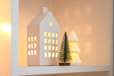 Ev şekilli mum tutacağı ve raflarda Noel ağaçları, yakın plan.