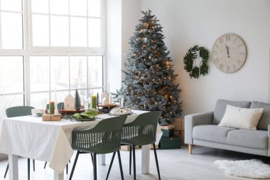 Odanın içinde Noel ağacı ve kanepesi olan yemek masası.