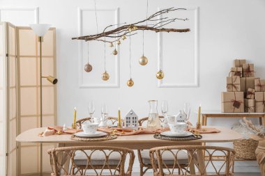 Yemek masası, ağaç dalları ve Noel topları olan ışık odasının içi.