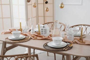 Yemek odasında mum tutucuları ve Noel baloları olan masa ayarları.