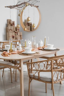 Yemek masası, ağaç dalları ve Noel topları olan ışık odasının içi.