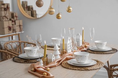 Yemek odasında mum tutucuları ve Noel baloları olan masa ayarları.