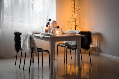 Yemek odasında yanan mumlar ve Noel baloları olan masa ayarı.