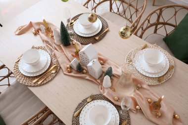 Yemek odasında mum tutucuları ve Noel ağaçları olan masa.