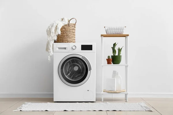 Interior of laundry room with washing machine, shelving unit and houseplants