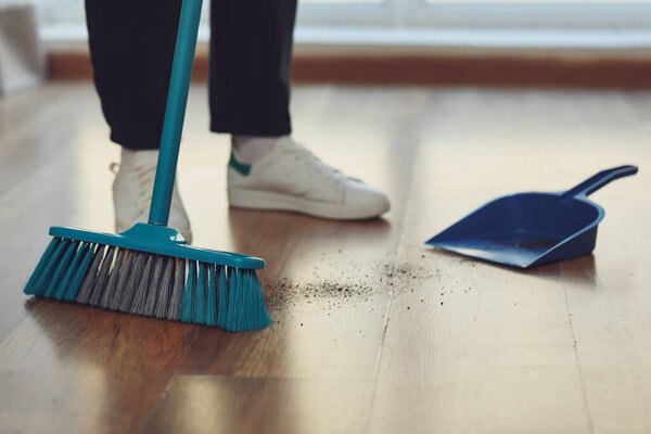 Woman sweeping floor with broom and dustpan