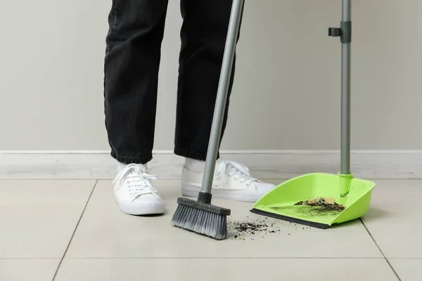 Woman sweeping tile floor with dustpan and broom