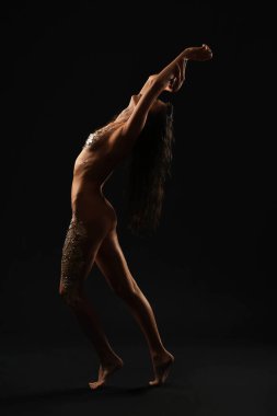 Koyu arkaplanda altın folyoyla çıplak genç bir kadın.