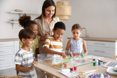 Ebru 'da yüksek lisans dersinde öğretmenli küçük çocuklar atölyede resim yapıyor.