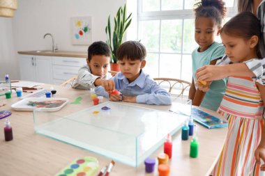 Ebru 'da yüksek lisans sınıfındaki küçük çocuklar atölyede resim yapıyor.