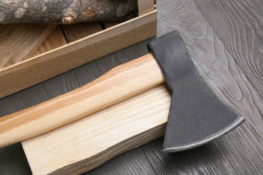 Koyu ahşap arka planda yakacak odunu olan balta, yakın plan.