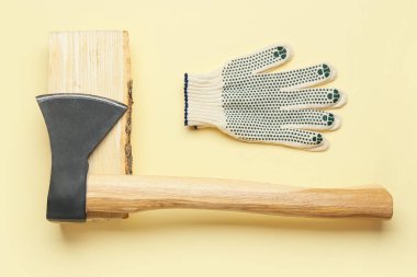 Yakacak odunlu balta ve sarı arka planda eldivenler.