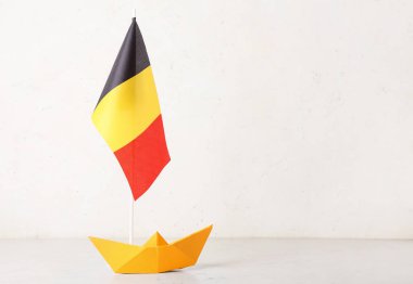 Kağıt gemi ve Belçika bayrağı ışık duvarının yanındaki masada.