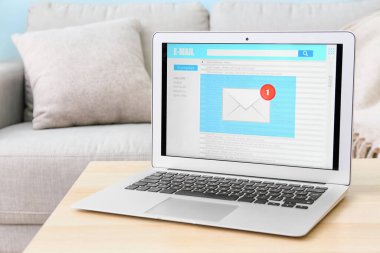 Odadaki ahşap masada açık e-posta kutusu olan modern bir laptop.