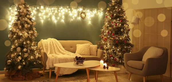Interior of dark living room with Christmas trees, cozy furniture and glowing lights