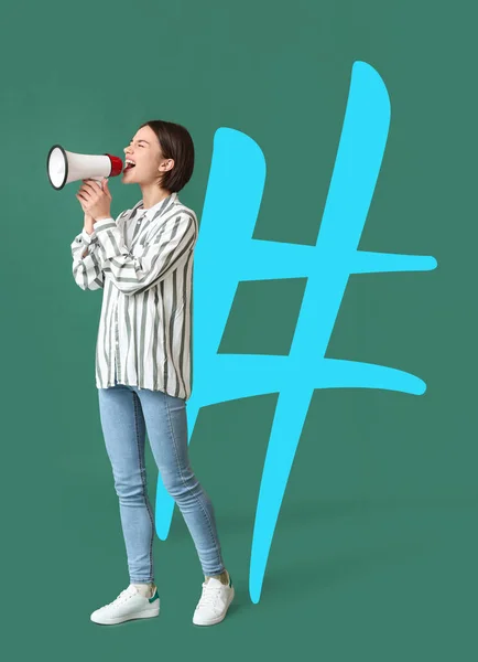 Young woman with megaphone and big hashtag on green background
