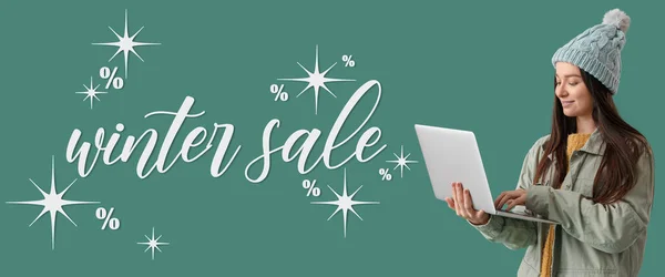 Young woman with laptop and text WINTER SALE on green background
