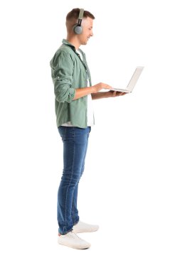 Kulaklık ve dizüstü bilgisayarı olan genç bir adam beyaz arka planda çalışıyor.