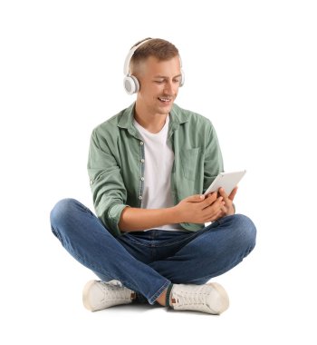 Kulaklığı ve tablet bilgisayarı olan genç adam beyaz arka planda çalışıyor.