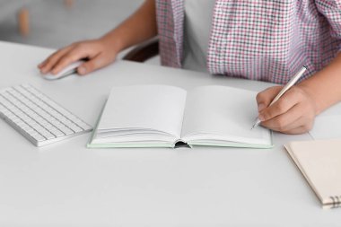 Genç adam evde internetten okurken deftere yazıyor, kapat.