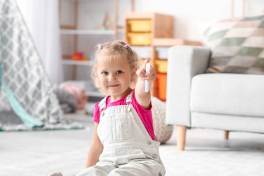 Evde yerde keçeli kalemleriyle oturan sevimli küçük kız.