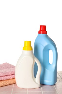 Çamaşır deterjanı ve havlular beyaz arka planda.