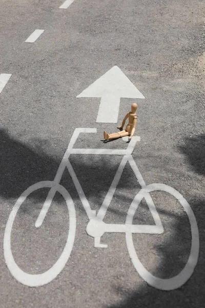 Wooden mannequin on road with bicycle signs in city