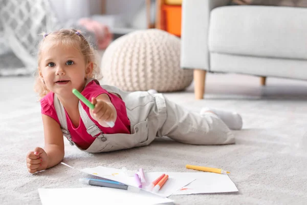 Cute little girl with felt-tip pen lying on floor at home