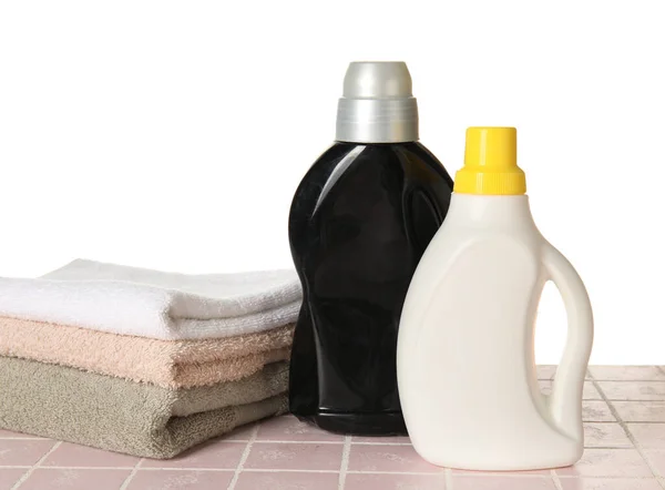 Laundry detergents and towels on table against white background