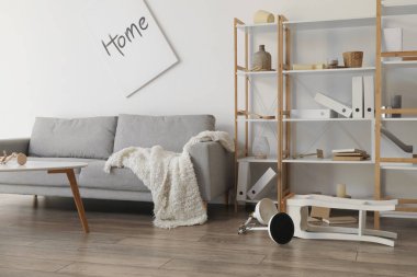 Gri kanepesi ve raf ünitesi olan dağınık oturma odasının içinde.