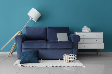 Mavi kanepesi ve standart lambası olan dağınık bir oturma odası.