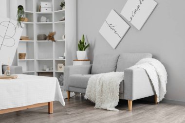 Oturma odasının iç tarafındaki ışıklı duvarın yanında ekoseli rahat bir kanepe.