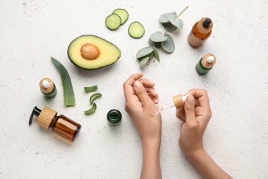 Temel yağ şişeleri ve doğal malzemelerle donatılmış kadın elleri.