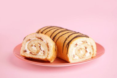 Pembe arka planda tatlı süngerli kek rulosu