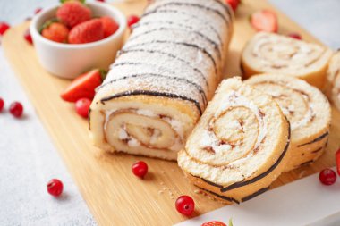 Lezzetli pandispanya rulosu ve taze böğürtlenlerle kesilmiş masa.