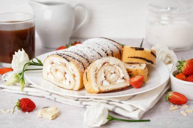 Lezzetli kek rulosu, taze çilek, çiçek dekoru ve açık arkaplanda bir fincan kahve.