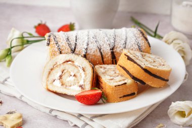 Lezzetli kek rulosu, taze çilek ve açık arkaplanda çiçek dekoru olan bir tabak.