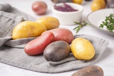 Aydınlık masada farklı tipte çiğ patatesler, yakın plan.