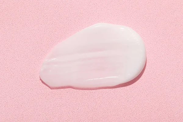 Smear of moisturizing cream on pink background