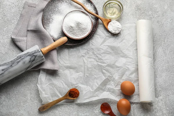 Baking paper with kitchen supplies and ingredients on grunge background