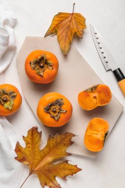 Olgun hurma ağaçları, sonbahar yaprakları ve açık arkaplanda bıçak olan tahta