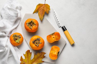 Olgun hurma ağaçları, sonbahar yaprakları ve açık arkaplanda bıçak olan tahta