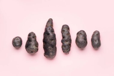 Pembe arka planda çiğ mor patates